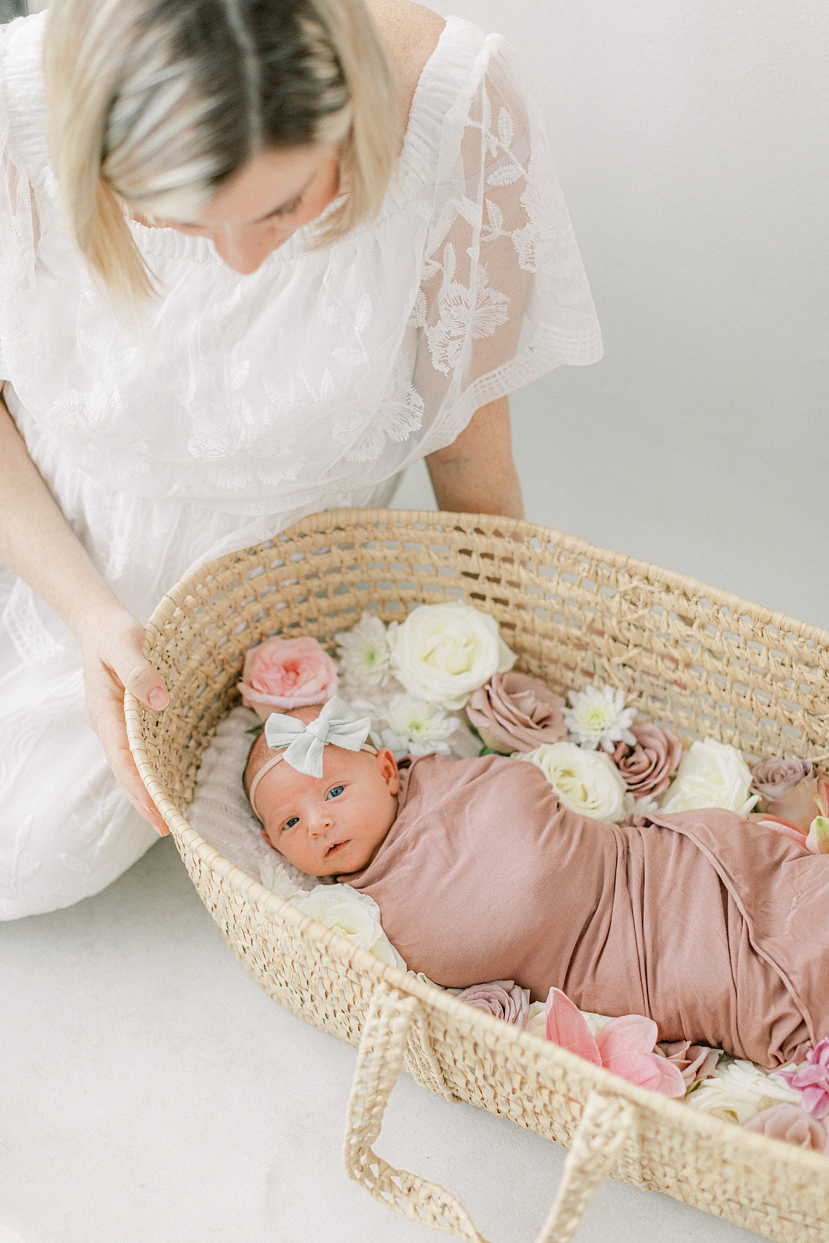 Baby girl in moses basket with flowers and Mom looking over her