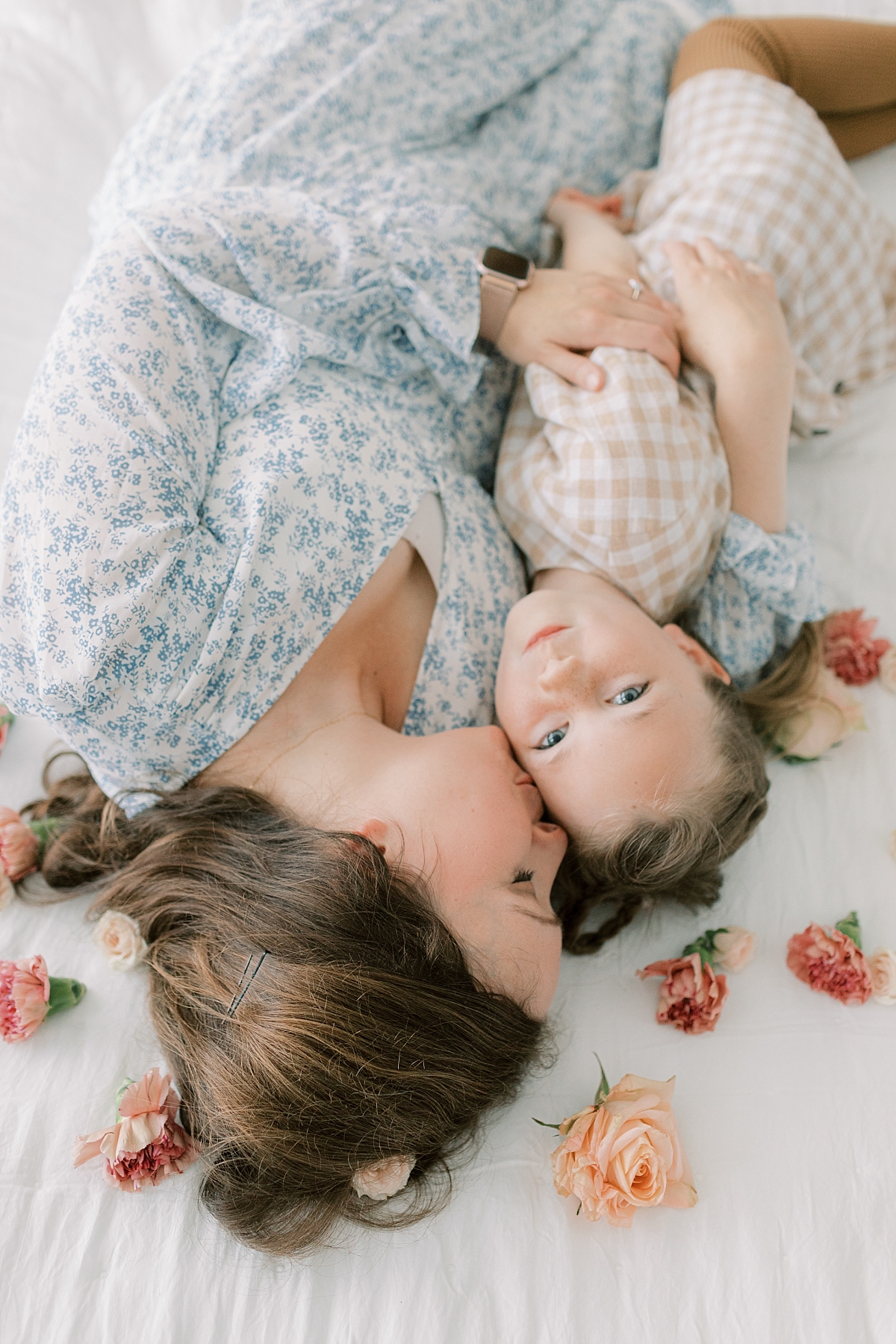 motherhood studio with mom laying and kissing daughter