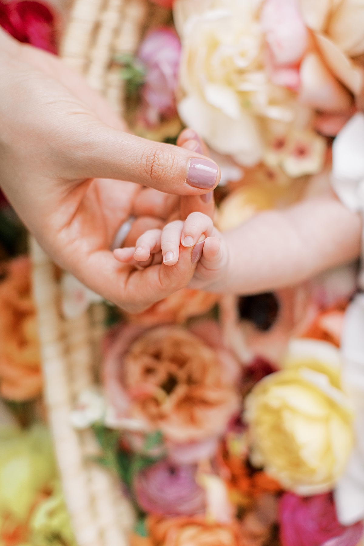 floral newborn session with baby holding mom's hand