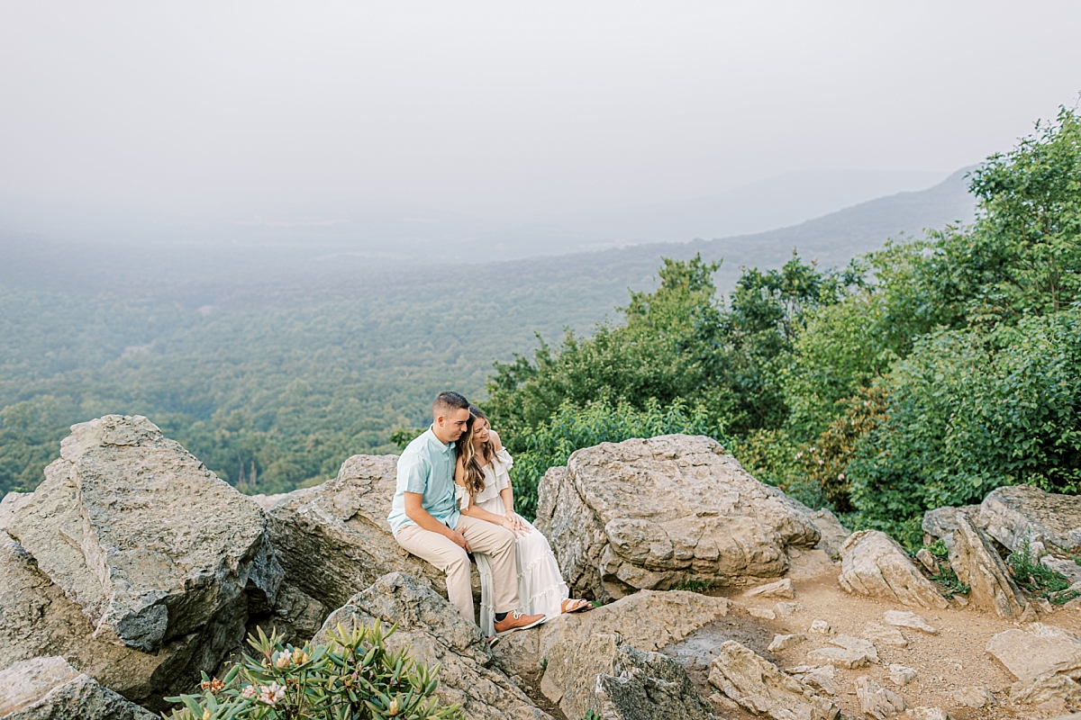 Engagement photo of a couple at Hawk Mountain Sanctuary in PA. The couple sits on rocks with a beautiful view