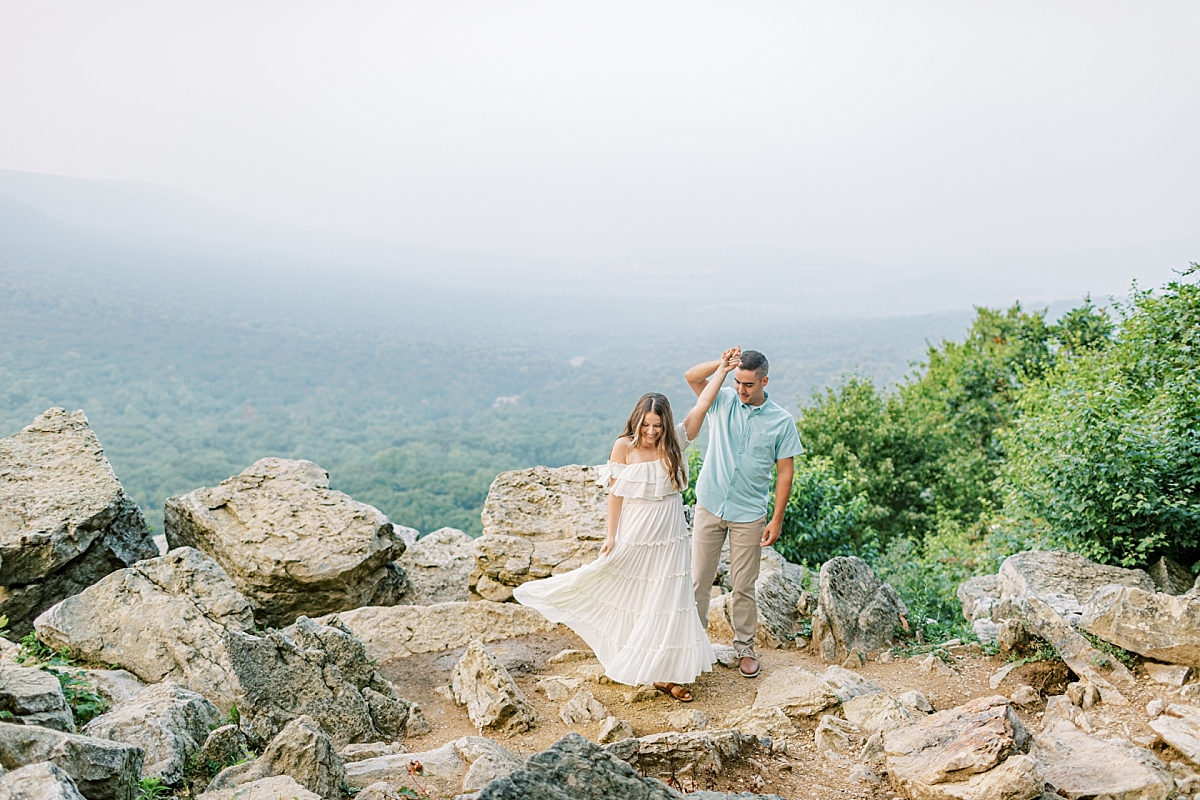 Engagement photo of a couple at Hawk Mountain Sanctuary in PA. The couple dances on rocks with a beautiful view