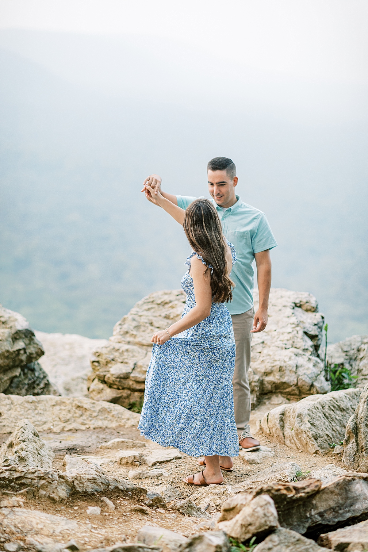 Engagement photo of a couple at Hawk Mountain Sanctuary in PA. The couple twirls on rocks with a beautiful view