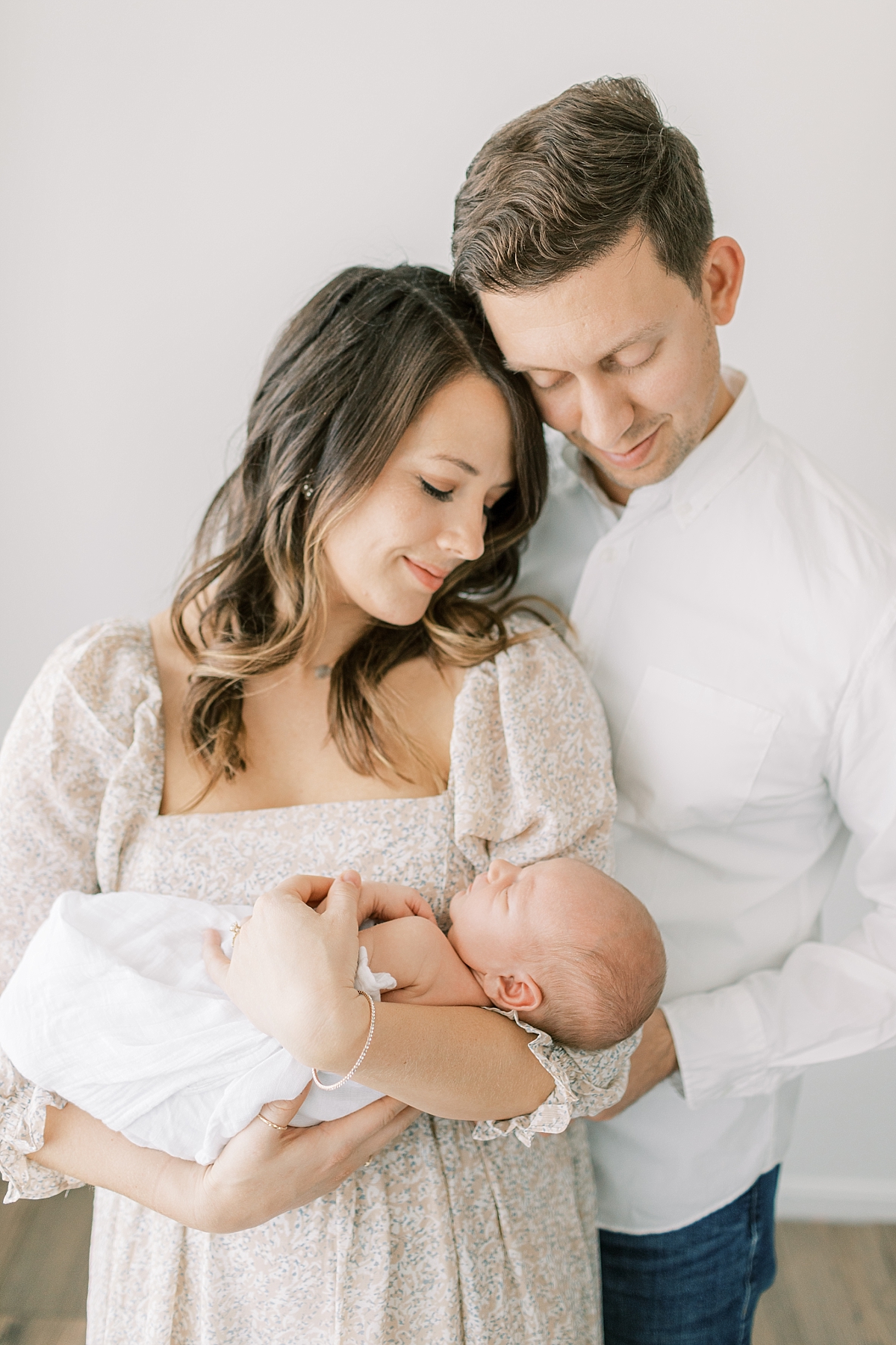 lifestyle newborn session with mom and dad looking down at baby